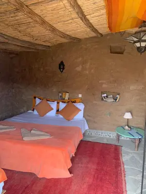 a bedroom with a bed and a table with a lamp at Maison Boutchrafine in Erfoud