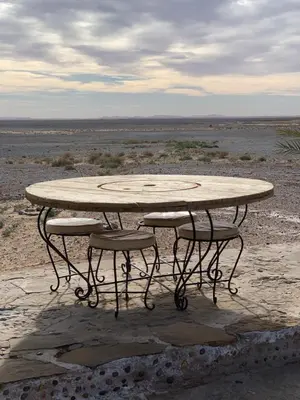 a table and two stools around a table in the desert at Maison Boutchrafine in Erfoud