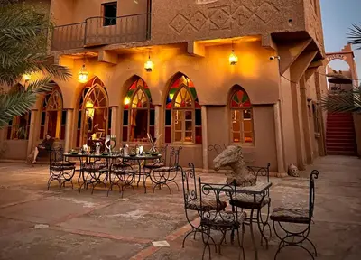 a patio with tables and chairs in front of a building at Hotel Carrefour des Nomades in Mhamid
