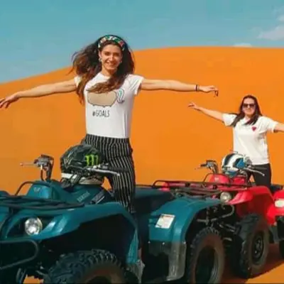 a woman is standing next to two atvs at Royal Luxury Cafe Du Sud in Merzouga