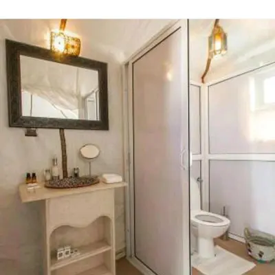 a bathroom with a shower and a toilet and a mirror at Royal Luxury Cafe Du Sud in Merzouga
