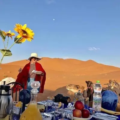 a woman standing in front of a table in the desert at Royal Luxury Cafe Du Sud in Merzouga