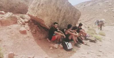 a group of people sitting on a rock in the desert at Maison d'Hôtes Agdal Telouet in Tiguidert