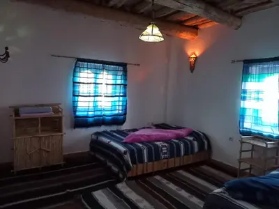 a bedroom with a bed and two windows at Maison d'Hôtes Agdal Telouet in Tiguidert