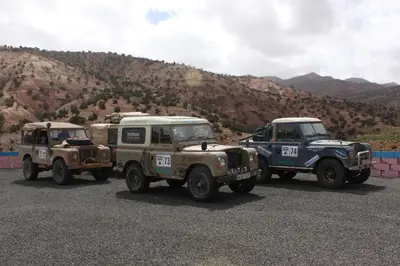 three military trucks parked next to a mountain at Maison d'Hôtes Agdal Telouet in Tiguidert