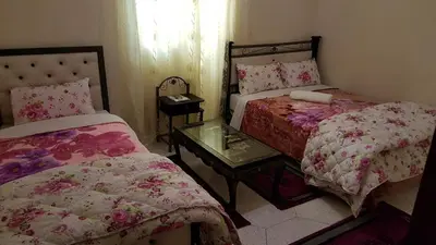 a bedroom with two beds and a table with a mirror at Hotel Nice 06 in Midelt