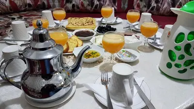 a table with a tea kettle and glasses of orange juice at Hotel Nice 06 in Midelt