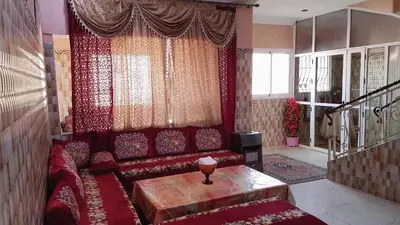 a living room with a red couch and a table at Hotel Nice 06 in Midelt