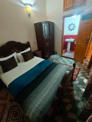 a bedroom with a bed and a bathroom with a sink at Riad lala Drissia in Gare de Tanger-Fès