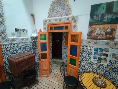 a room with a bed and a table and chairs at Riad lala Drissia in Gare de Tanger-Fès