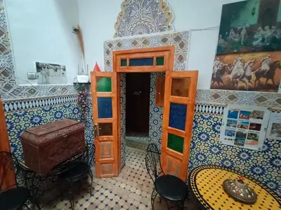 a room with a bed and a table and chairs at Riad lala Drissia in Gare de Tanger-Fès