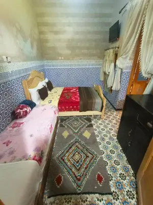 a small bedroom with two beds and a rug at Riad lala Drissia in Gare de Tanger-Fès