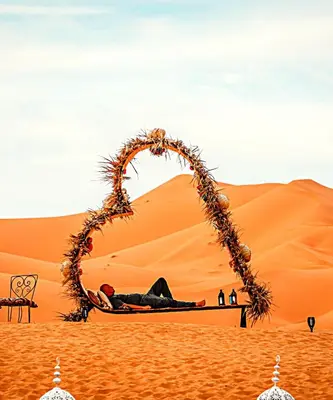 a man laying on a bed in the desert at Africa Luxury Camps - Merzouga Premium Camp in Merzouga