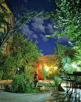 a garden at night with a table and chairs at Riad Fennec Sahara in Zagora