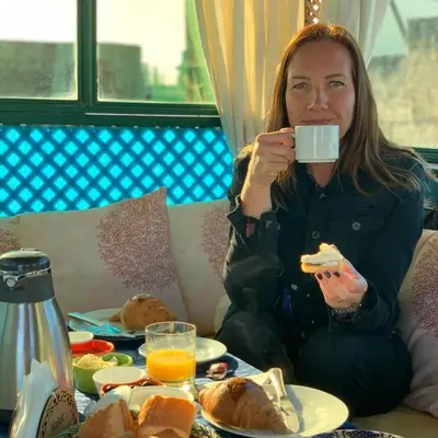 a woman sitting at a table drinking a cup of coffee at Dar Belmamoun in Fès