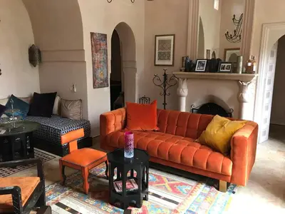 a living room with an orange couch and a fireplace at Villa #1 ‘Rosalie’ in Marrakech