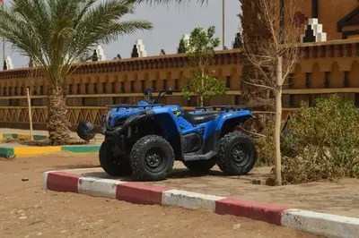 a blue atv parked on a curb next to a building at Residence Touristique Merzouga in Merzouga