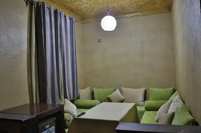 a living room with a couch with green pillows at Residence Touristique Merzouga in Merzouga