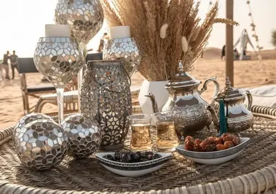 a table with vases and plates of food on the beach at Deep Desert Camp in Merzouga