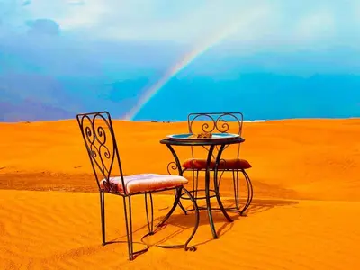 two chairs and a table in the desert at Deep Desert Camp in Merzouga