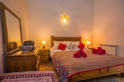 a bedroom with two beds with red pillows and a mirror at Riad Zina Fes - Elegance in the Heart of Fes in Fès