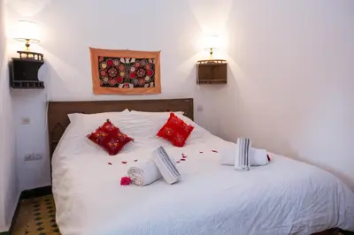 a bed with red and white pillows and flowers on it at Riad Zina Fes - Elegance in the Heart of Fes in Fès
