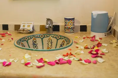 a bathroom sink with fallen flowers on a counter at Riad Zina Fes - Elegance in the Heart of Fes in Fès