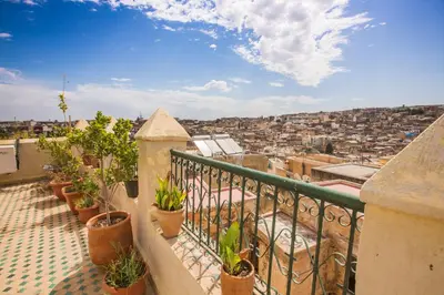 a balcony with potted plants and a view of a city at Riad Zina Fes - Elegance in the Heart of Fes in Fès