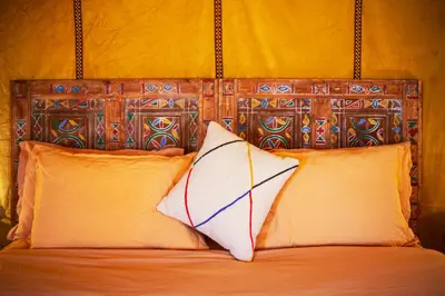 a bed with a wooden head board with two pillows at Auberge Bivouac La Belle Etoile in Merzouga