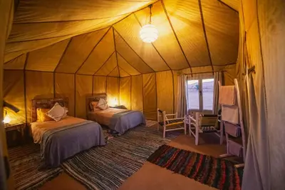 a bedroom with two beds in a tent at Auberge Bivouac La Belle Etoile in Merzouga
