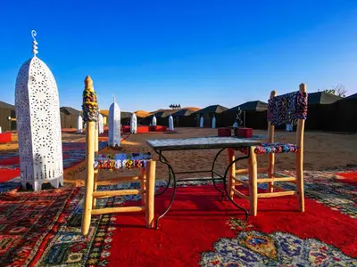a table and two chairs on a rug with tents at Auberge Bivouac La Belle Etoile in Merzouga