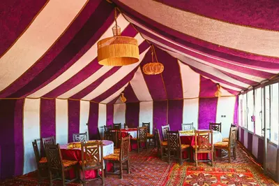 a dining room with purple walls and tables and chairs at Auberge Bivouac La Belle Etoile in Merzouga