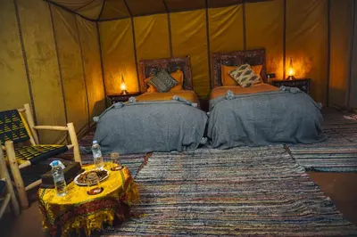 a bedroom with two beds and a table in a tent at Auberge Bivouac La Belle Etoile in Merzouga