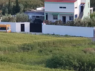 a house with a white fence in front of a field at BELLE MAISON AU COEUR DES MONTAGNES DE TAZA à moins de 10 minutes de l'AGORA PARK in Taza