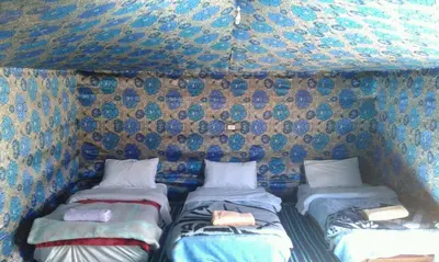 a couple of beds in a room with a wall at Chez zakaria luxury camp merzouga in Merzouga