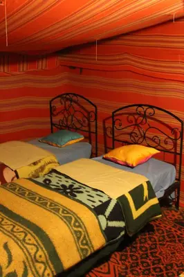 two beds in a room with red and orange walls at Chez zakaria luxury camp merzouga in Merzouga