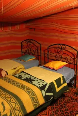 two beds in a room with red walls at Chez zakaria luxury camp merzouga in Merzouga