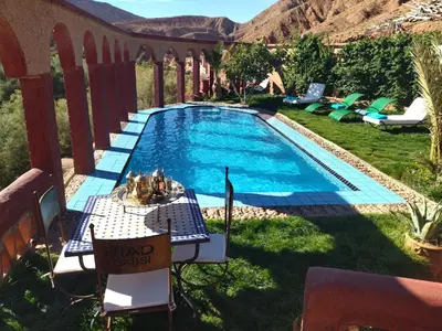 a pool with a table and chairs next to it at Riad Gabsi Dades in Boumalne