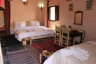 a bedroom with two beds and a table and a desk at Riad Gabsi Dades in Boumalne