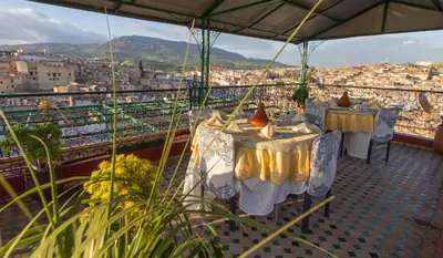 two tables on a balcony with a view of a city at Riad El Bacha in Fès