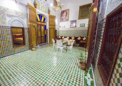 a room with a table and chairs on a tiled floor at Riad El Bacha in Fès
