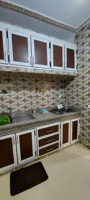 a kitchen with white cabinets and a brick wall at حدائق إفران in Ifrane