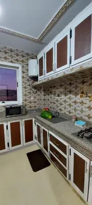 a kitchen with white cabinets and a tv on the wall at حدائق إفران in Ifrane