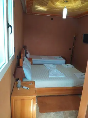 a small bedroom with two beds and a lamp at Bio Palace Hotel in Tinerhir