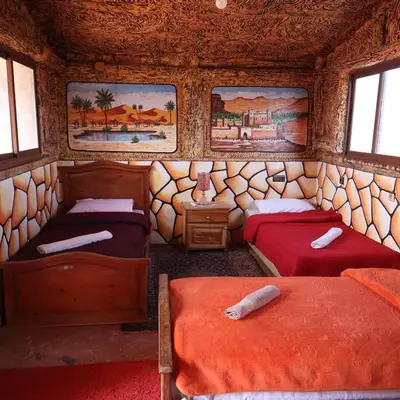 a room with two beds and paintings on the wall at Bio Palace Hotel in Tinerhir