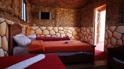 a bedroom with two beds and a tv on the wall at Bio Palace Hotel in Tinerhir