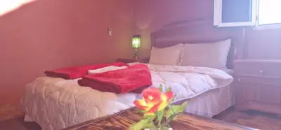 a bedroom with a bed with red blankets on it at Bio Palace Hotel in Tinerhir