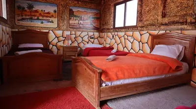 a bedroom with two beds in a room with wooden walls at Bio Palace Hotel in Tinerhir