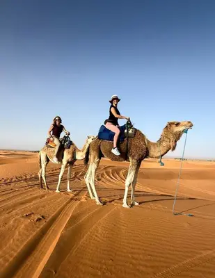 three people riding on the camel in the desert at Sahara Sunset Camp M'hamid in Mhamid