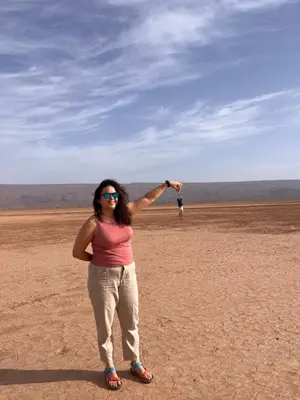a woman standing in the desert holding up a kite at Sahara Sunset Camp M'hamid in Mhamid